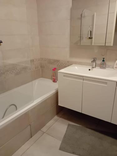 La salle de bains blanche est pourvue d'un lavabo, d'une baignoire et d'une baignoire. dans l'établissement Appartement de standing - 3 chambres - 8 personnes - Grand Lyon, à Villeurbanne