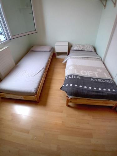 - 2 lits dans une petite chambre dotée de parquet dans l'établissement Appartement de standing - 3 chambres - 8 personnes - Grand Lyon, à Villeurbanne