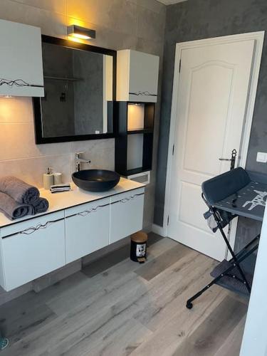 La salle de bains est pourvue d'un lavabo, d'un miroir et d'une porte. dans l'établissement Villa piscine et jeux Normande, à Selles