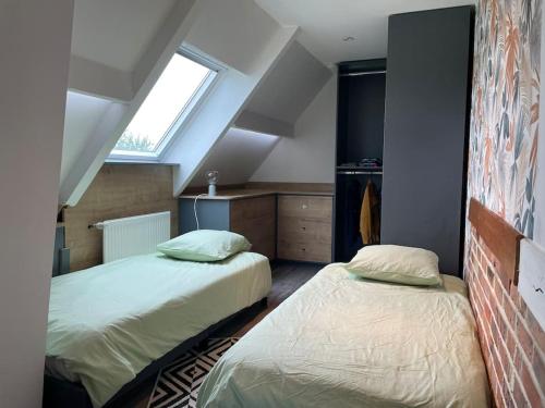 - une chambre mansardée avec 2 lits et une fenêtre dans l'établissement Villa piscine et jeux Normande, à Selles