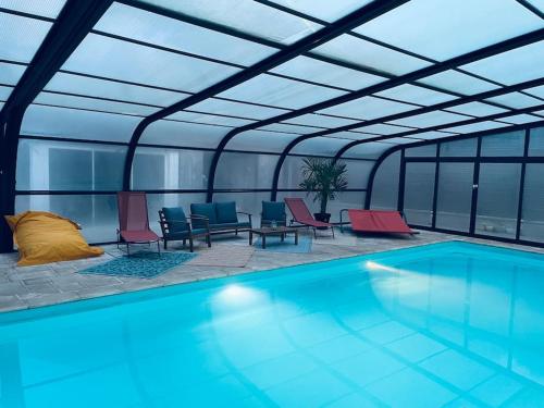 une piscine avec des chaises rouges et bleues dans un immeuble dans l'établissement Villa piscine et jeux Normande, à Selles