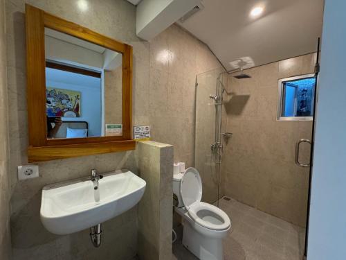 a bathroom with a sink and a toilet and a mirror at Made Arsa Homestay in Ubud