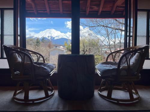 two chairs in front of a window with a mountain view at OSHI-KIKUYA A Historic Mount Fuji Stay in Fujiyoshida