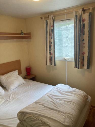 une chambre avec un lit et une fenêtre avec des rideaux dans l'établissement Mobil Home 2 Chambre G26, à Saint-Georges-de-Didonne