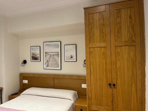 a bedroom with a wooden cabinet and a bed at Pension Angelines, Sneuu Hostel Santander in Santander