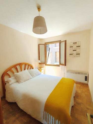 a bedroom with a large bed with a yellow blanket at Peña Telera Petfriendly - Arafita Apartamentos in El Pueyo de Jaca