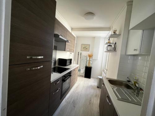 - une cuisine avec des placards en bois sombre et un évier dans l'établissement EVA Bayeux, à Bayeux