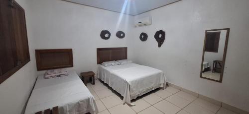 a white bedroom with a bed and a mirror at Espaço Sairé - 8 minutos da Praia in Alter do Chao