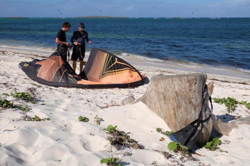 two men standing next to a tent on the beach at Varatraza Wind Riders in Diego Suarez
