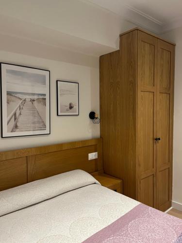 a bedroom with a bed and a wooden cabinet at Pension Angelines, Sneuu Hostel Santander in Santander
