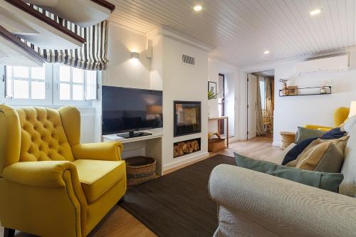 a living room with a yellow chair and a television at Villa Mau Maria incl Parking by Home Sweet Home Aveiro in Aveiro