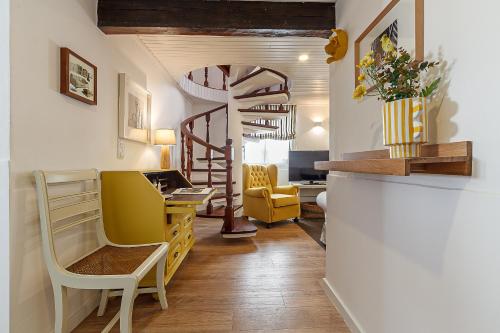 a living room with yellow chairs and a spiral staircase at Villa Mau Maria incl Parking by Home Sweet Home Aveiro in Aveiro