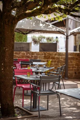 a group of tables and chairs under a tree at Logis Hostellerie de l'Abbaye in Celles-sur-Belle