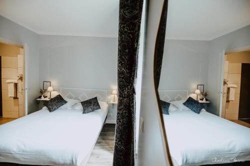 two beds in a room with a mirror at Grand Hotel Des Bains & Villas des Bains in Vals-les-Bains
