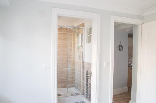 a glass shower in a bathroom with white walls at Palomar in Falmouth