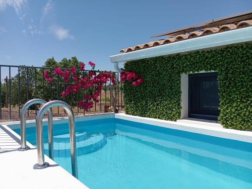 a swimming pool in front of a building with pink flowers at Alojamiento rural La Moravieta in Pozoamargo