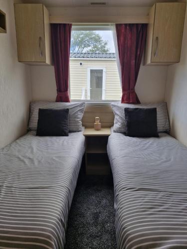 two beds in a small room with a window at Haven Skegness 20 Donna Nook in Skegness