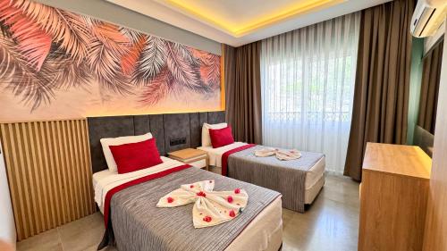Una habitación de hotel con dos camas y un cuadro en la pared. en Gürol Apart, en Fethiye