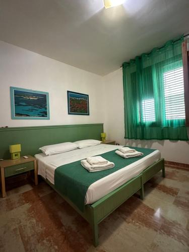 a bedroom with a bed with green sheets and a window at Isoladelmiele in Marettimo