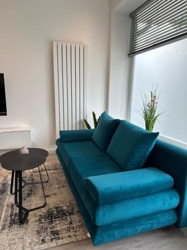 a blue couch in a living room with a table at City Suite Drita in Alsdorf