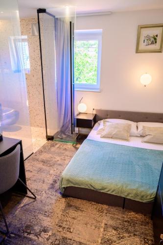a bedroom with a bed and a glass shower at Hotel Krilo in Podstrana