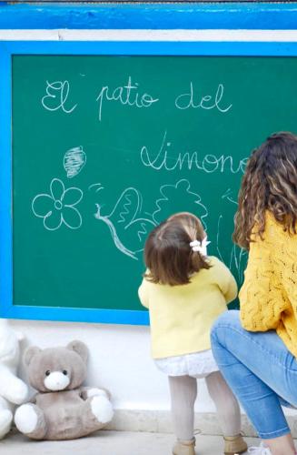 two children sitting in front of a green chalkboard at El Patio del Limonero in Écija