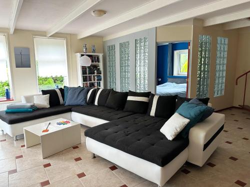 a living room with a black and white couch at Vakantiehuis het Voorhuis op Landgoed koepeltjesplaats in Gaast
