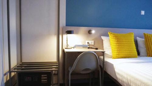 a bedroom with a bed with a yellow pillow and a desk at Hotel Fogo Amsterdam in Amsterdam