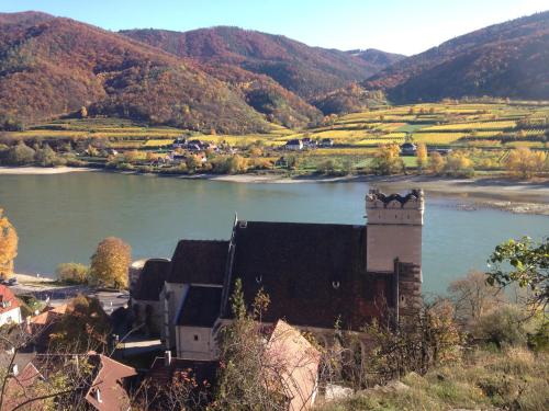 a building next to a river with a mountain at Apartement Schlaf Gut - mitten in der Wachau in Weissenkirchen in der Wachau