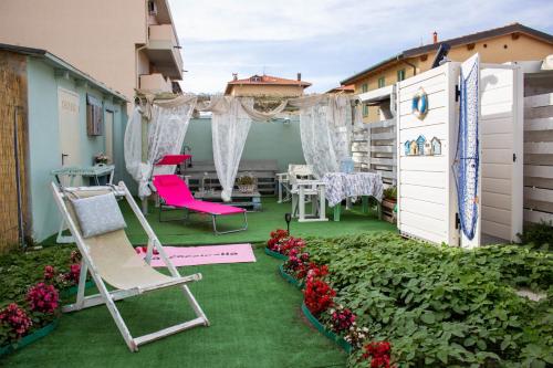 a patio with chairs and a table and flowers at la coccinella in Marina di Pisa