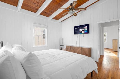 a white bedroom with a large bed and a flat screen tv at Bummer Busters in Myrtle Beach