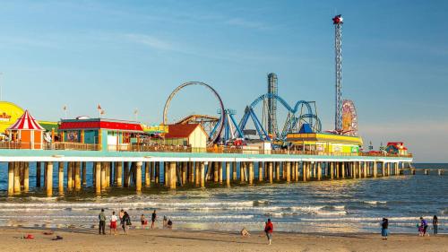 Un muelle con un parque de atracciones y gente en la playa. en Beach Blanket Bungalow - A Wonderful townhome near the beach, en Galveston