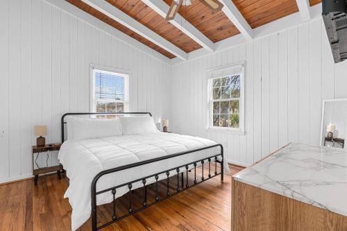 a white bedroom with a bed and a wooden floor at Bummer Busters in Myrtle Beach
