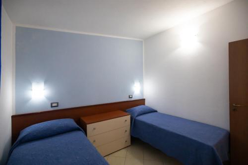 a bedroom with two beds and a dresser in it at Villaggio Camping Fiorina in Capo Vaticano