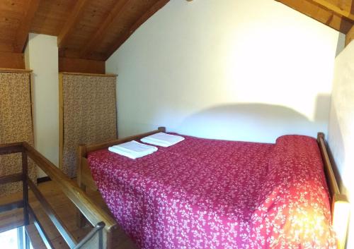 a bedroom with a red bed with two towels on it at Agriturismo La Fonte Di Mariella in Gravedona