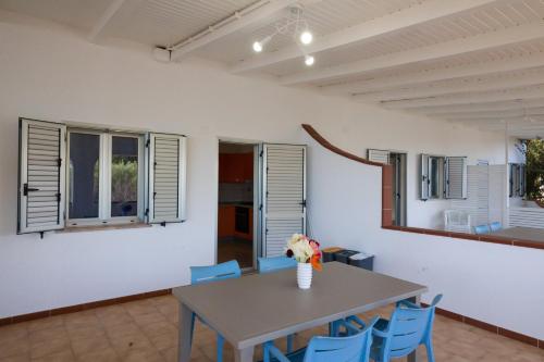 a dining room with a table and blue chairs at Villaggio Camping Fiorina in Capo Vaticano