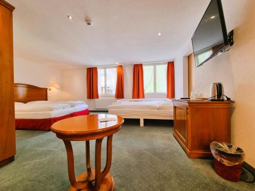 a hotel room with two beds and a table at Self-Service Guesthouse Berggeist in Saas-Fee