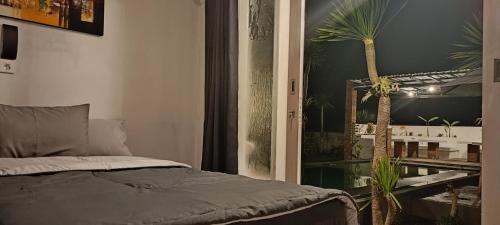 a bedroom with a bed and a palm tree at Batur Homestay and Lodge in Bangli