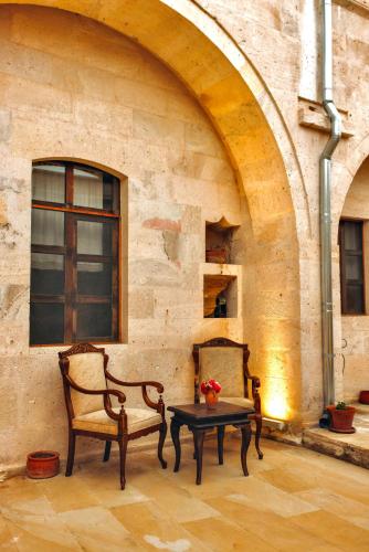 two chairs and a table in front of a building at Solin Cave Cappadocia in Mustafapaşa
