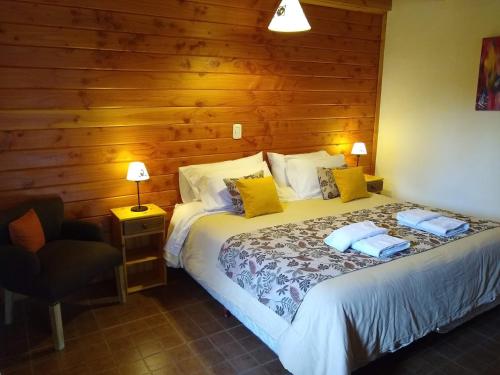 a bedroom with a bed and a chair in it at La Aljaba in El Bolsón