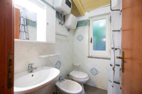 a bathroom with a sink and a toilet and a window at Villaggio Camping Fiorina in Capo Vaticano