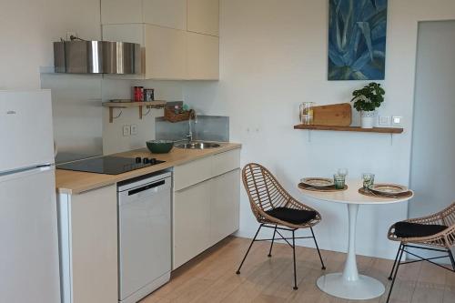 une cuisine avec des armoires blanches et une table et des chaises dans l'établissement T2 terrasse arborée vue mer, à Hyères