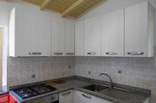 a kitchen with white cabinets and a sink at Villaggio Camping Fiorina in Capo Vaticano