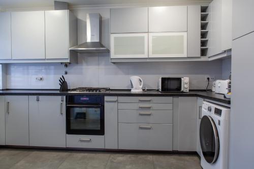 a kitchen with white cabinets and a stove top oven at T3 Casa Central in Sesimbra