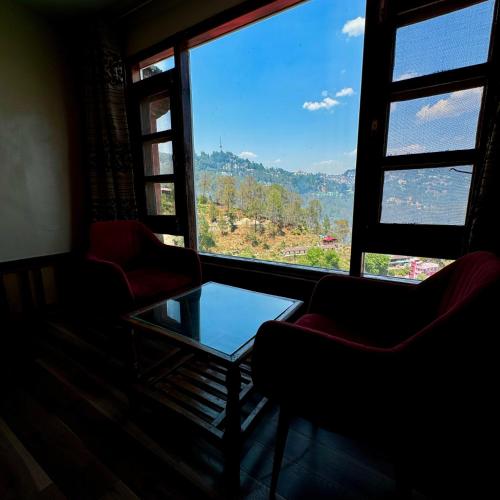 a room with two chairs and a table and a window at Hotel Apple Regency in Shimla