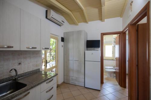 a kitchen with a sink and a white refrigerator at Villaggio Camping Fiorina in Capo Vaticano