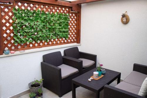 a patio with two chairs and a table and a green hedge at Lovely apartment in the heart of Pula in Pula