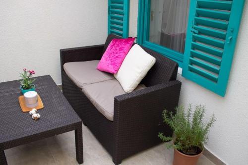 a black wicker chair with a pink pillow and a table at Lovely apartment in the heart of Pula in Pula