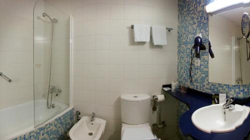 a bathroom with a toilet and a sink and a shower at Hotel Cosmopol in Laredo
