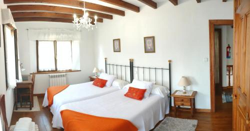 two beds in a bedroom with white walls and wood floors at Casa de la Fuente Santillana del Mar in Santillana del Mar